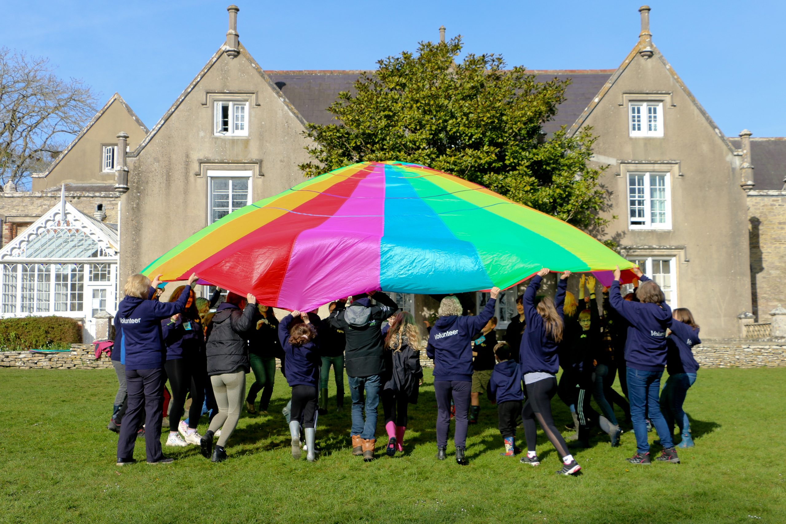 children and adults holding a parachute
